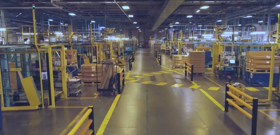 Vaste atelier de production industrielle avec machines et postes de travail sécurisés pour la fabrication de couvercles en aluminium.